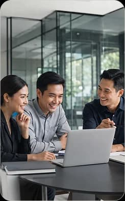 Three Mooselab teammates reviewing work together on a laptop in a glass-walled meeting room